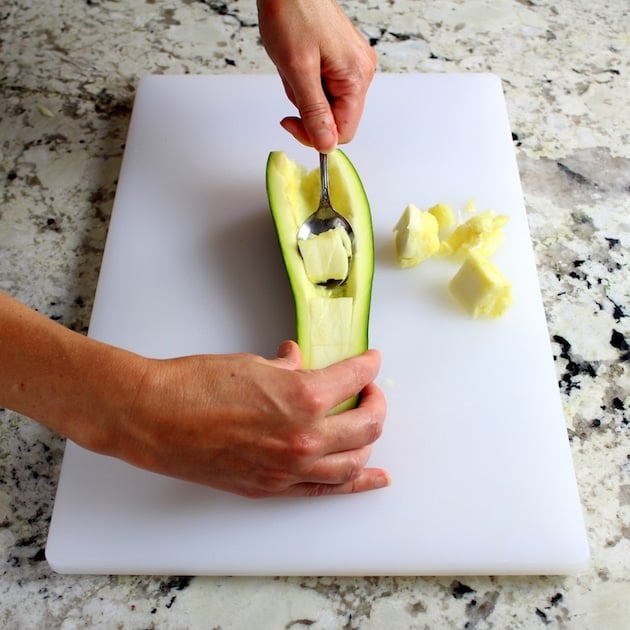 scooping out center of sliced squash