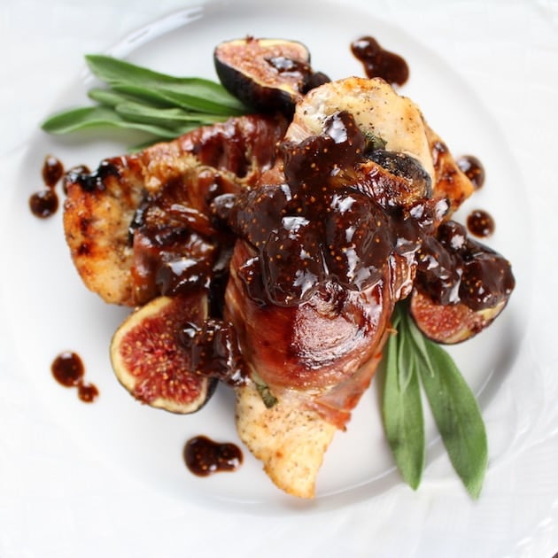 close up plate of chicken breasts wrapped in prosciutto with fig sauce and fresh figs