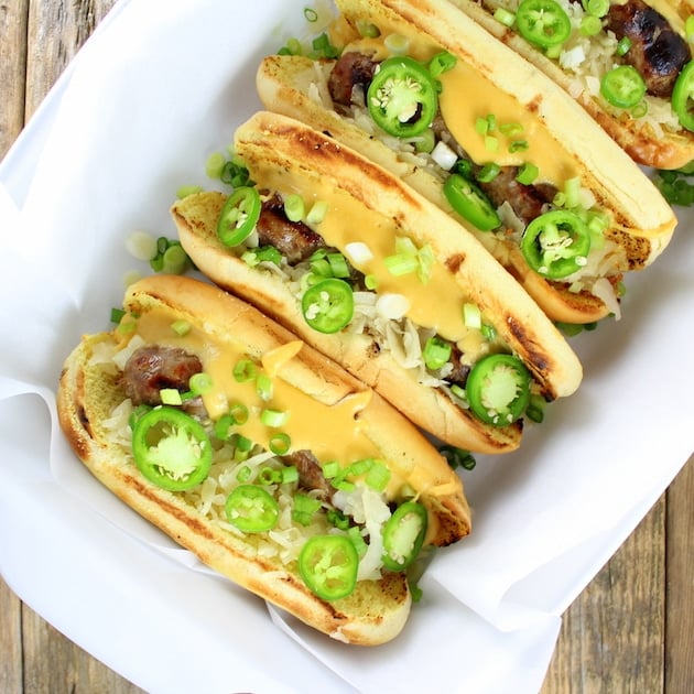 4 Cheesy Beer Brats with Fried Pickles in buns in a casserole dish