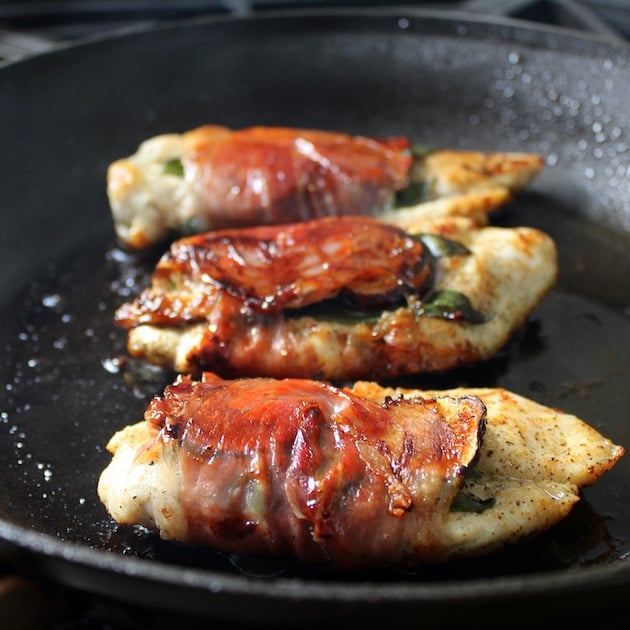 chicken wrapped in prosciutto frying in saute pan