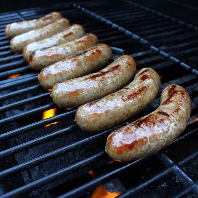 8 Beer Brats lined up cooking on the grill 