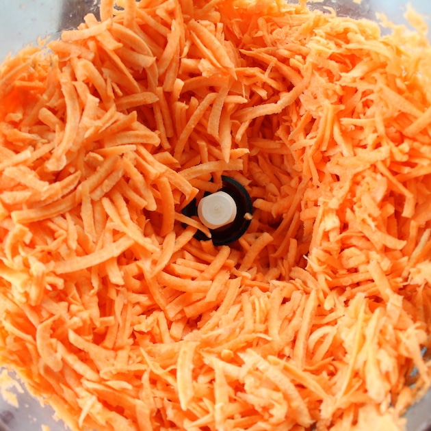 Close up shredded sweet potatoes in a food processor