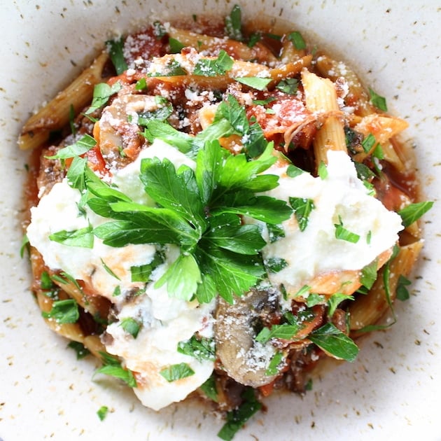 Ricotta and parmesan on a bowl of penne pasta and Beef Ragu