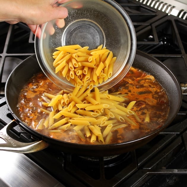 Adding penne pasta to saute pan with Beef Ragu