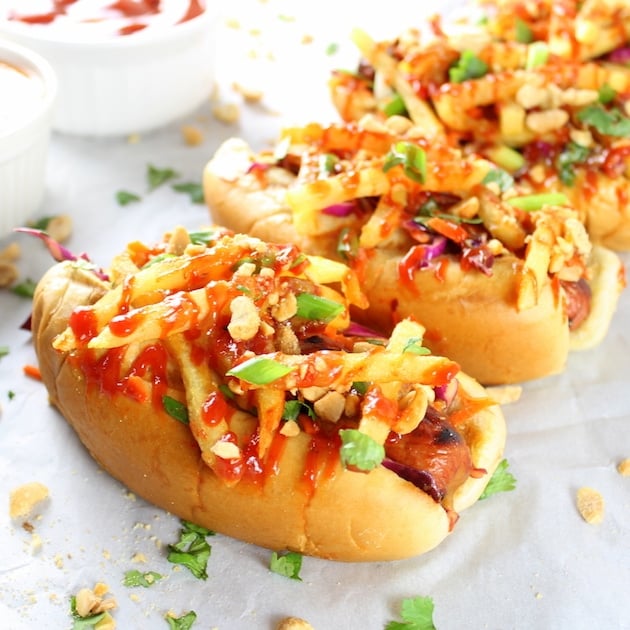 Eye level close up asian hot dogs with slaw, french fries, and spicy ketchup