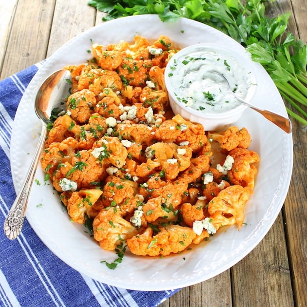 White plate full of Orange Buffalo Cauliflower with a dish of Blue Cheese Sauce