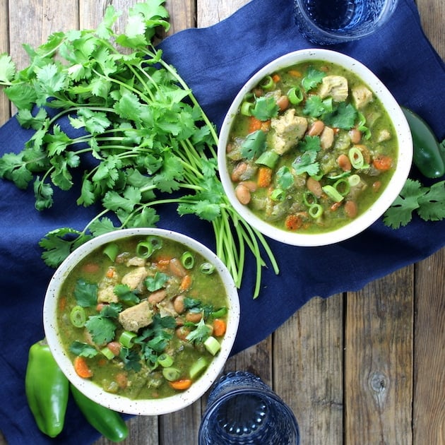 Two bowls of Chicken and Green Chile Verde Soup with bunch of parsley