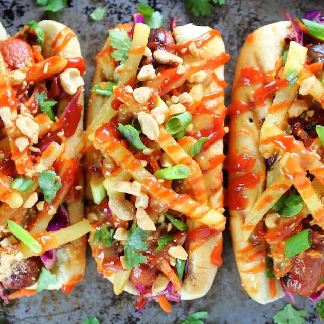 Three asian hot dogs with slaw, french fries, and ketchup