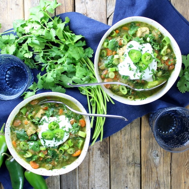 Two bowls of Chicken and Green Chile Verde Soup on a farm table