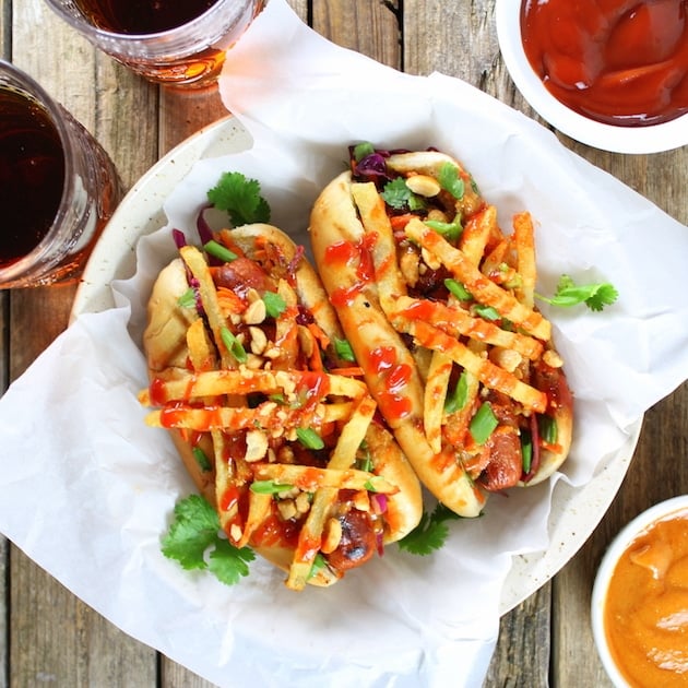 Two Asian Pad Thai hot dogs with slaw, french fries, spicy ketchup, and peanuts