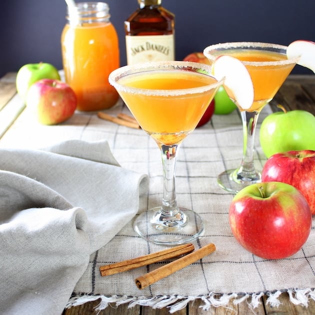 Apple Cider Honey Jack Martinis on table with cinnamon sticks and whole apples