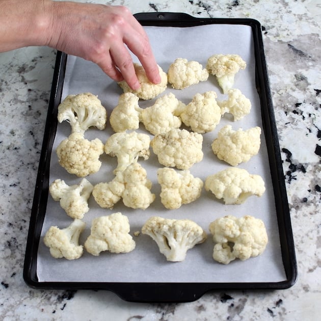 Placing cauliflower florets on a parchment-lined baking sheet