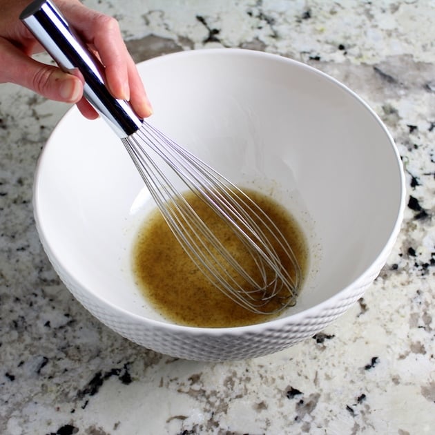 Whisking spices with olive oil in large white bowl