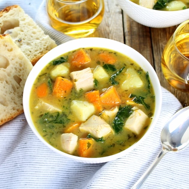 Bowl of Kale and Butternut Squash Turkey Soup on table with sourdough bread