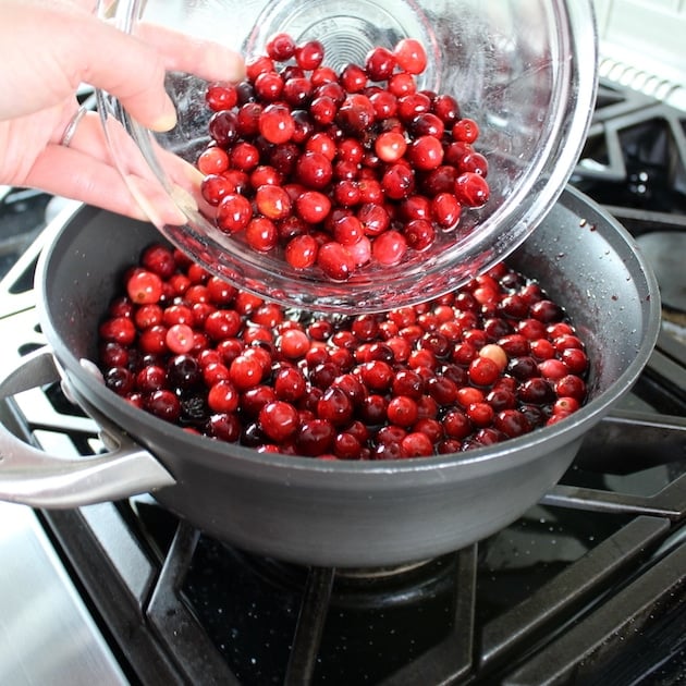 adding fresh cranberries to saucepan 