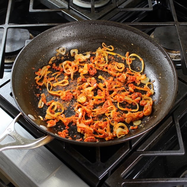 shallots and ginger with red curry paste in saute pan 