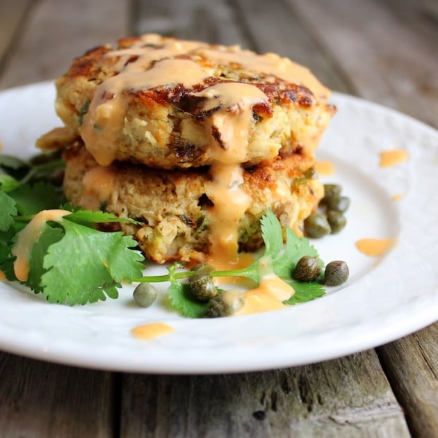 Two tuna cakes stacked on a plate topped with sriracha aioli