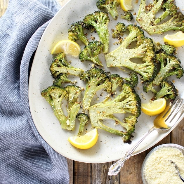 Roasted Broccoli slices on a platter with lemon wedges