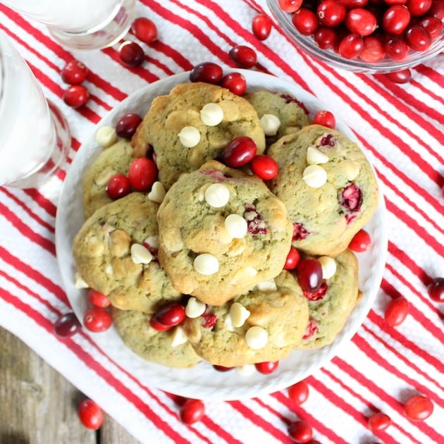 A plate stacked with Cranberry Orange Cookies with two glasses of milk.