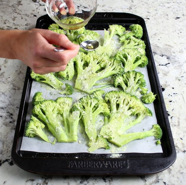 Adding olive oil to broccoli before roasting