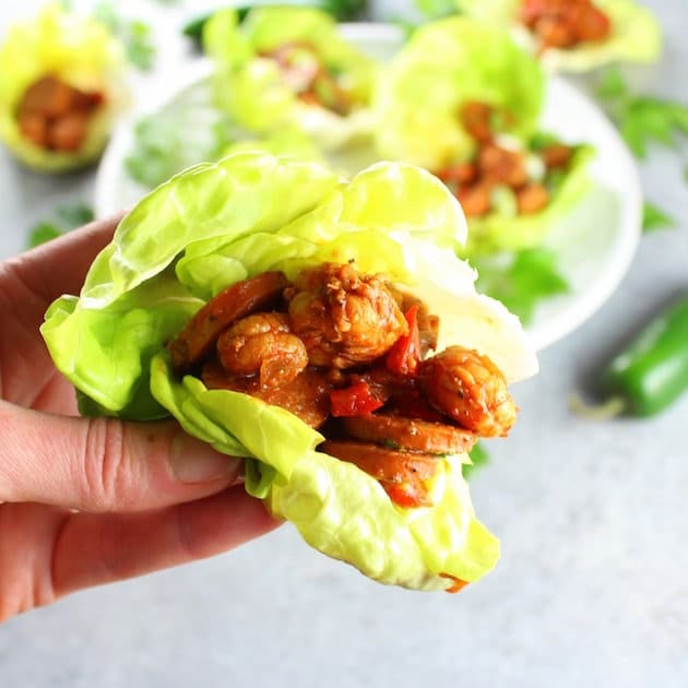 hand holding a lettuce wrap with cajun sausage and shrimp