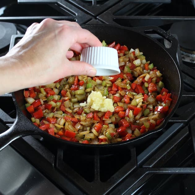 Adding garlic to skillet of veggies