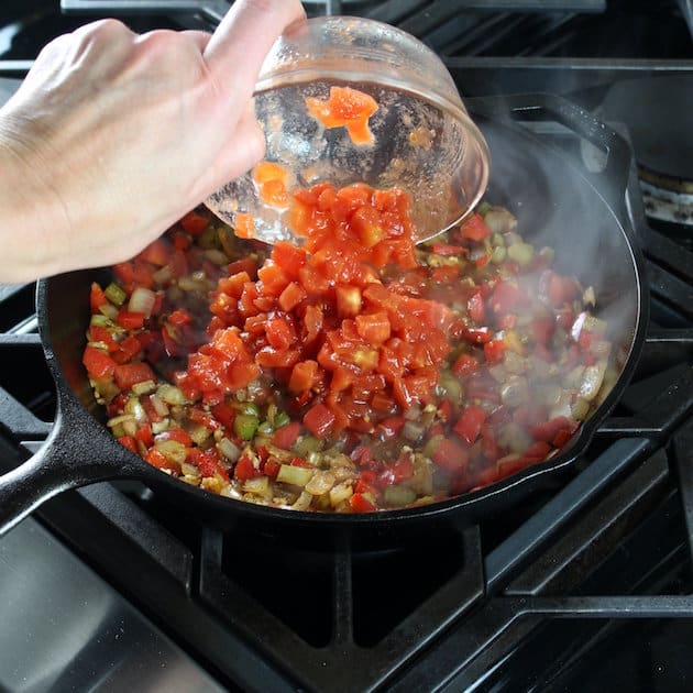 Adding diced tomatoes to skillet