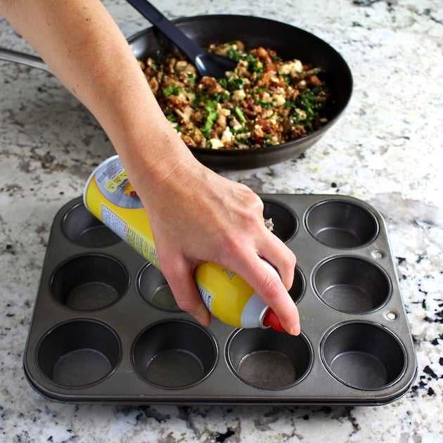 Spraying muffin tin with cooking spray