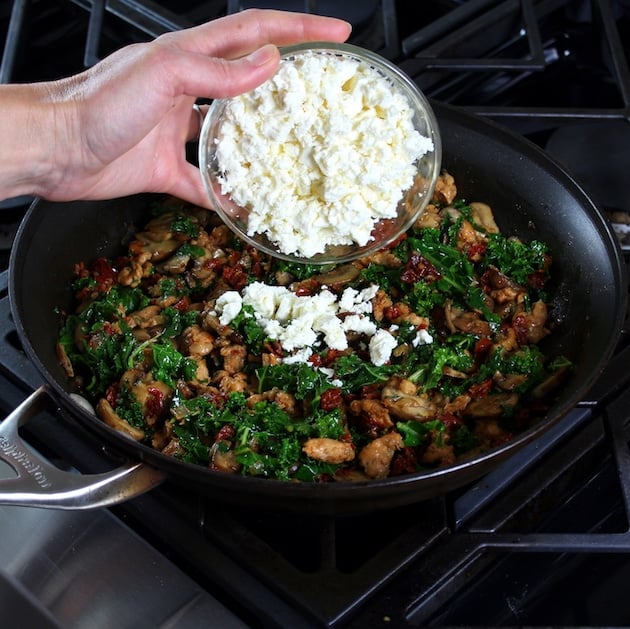 adding feta to saute pan with breakfast ingredients