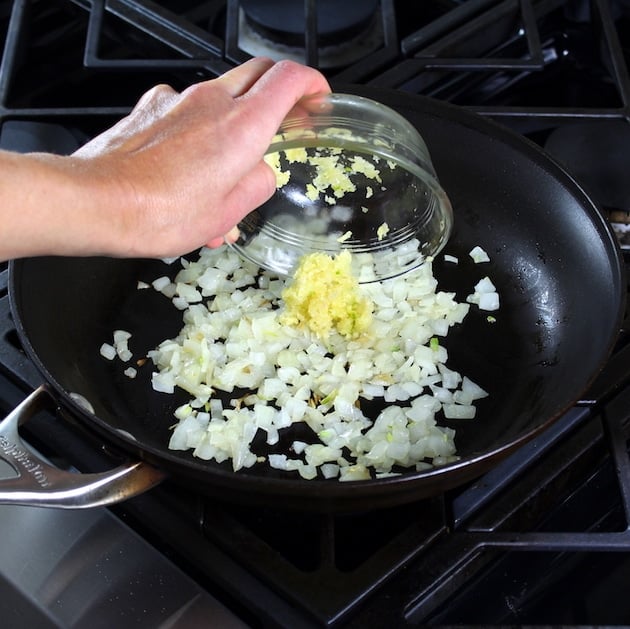 adding garlic to saute pan with onions