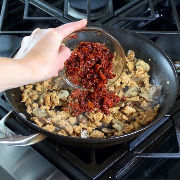 Adding sundried tomatoes to pay with mushrooms and onions