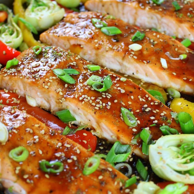 A close up of Salmon filets roasted with honey soy glaze, sesame seeds, and green onions