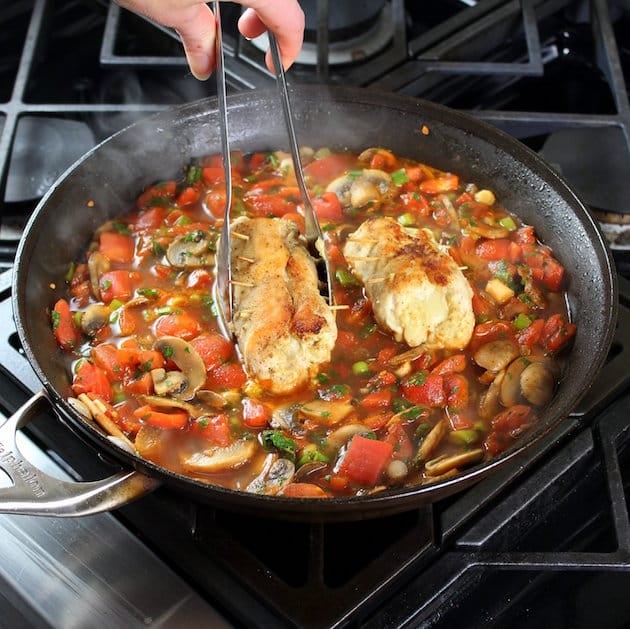 Adding chicken breasts to saute pan with italian red sauce