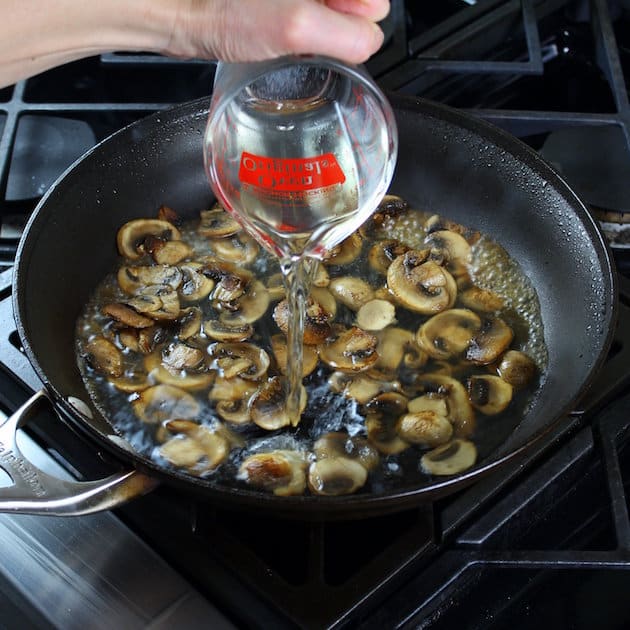 Adding white wine to mushrooms in saute pan