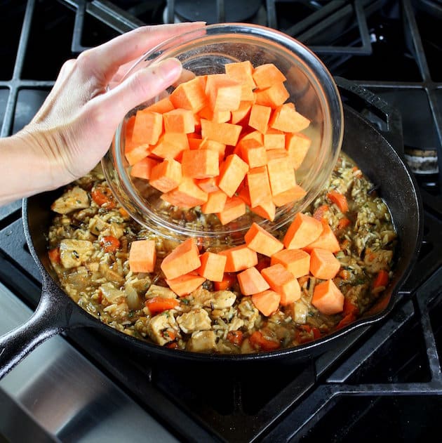 Adding diced sweet potatoes to chicken rice dinner skillet