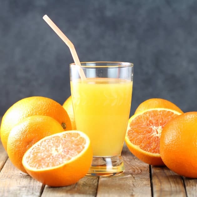 Two oranges and a glass of orange juice