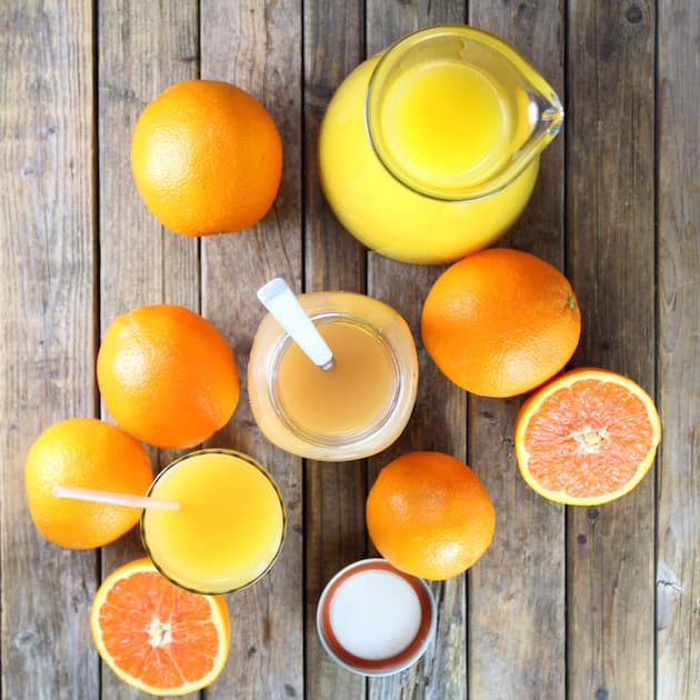 Two oranges sitting on top of a wooden table