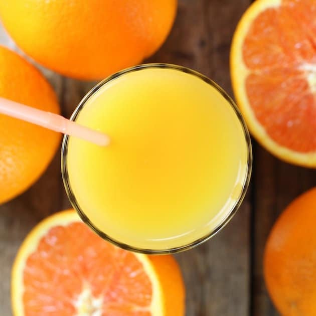 Two oranges and a glass of orange juice