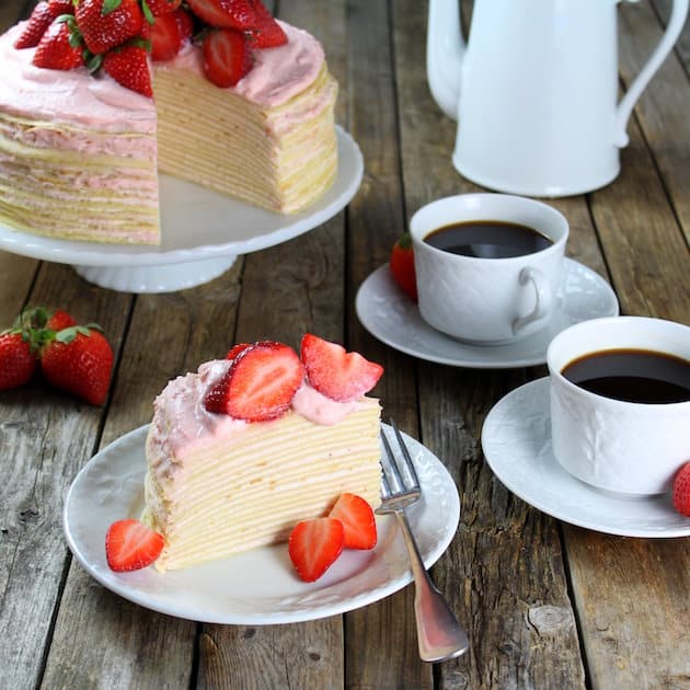 Strawberry Lemon Creme Crepe Cake on a table with coffee