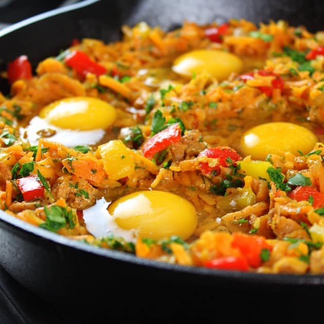 Close up eye level eggs cooking in a breakfast skillet on stovetop