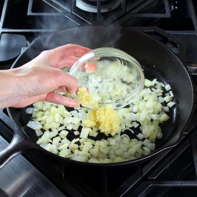 adding garlic to onions in a saute pan