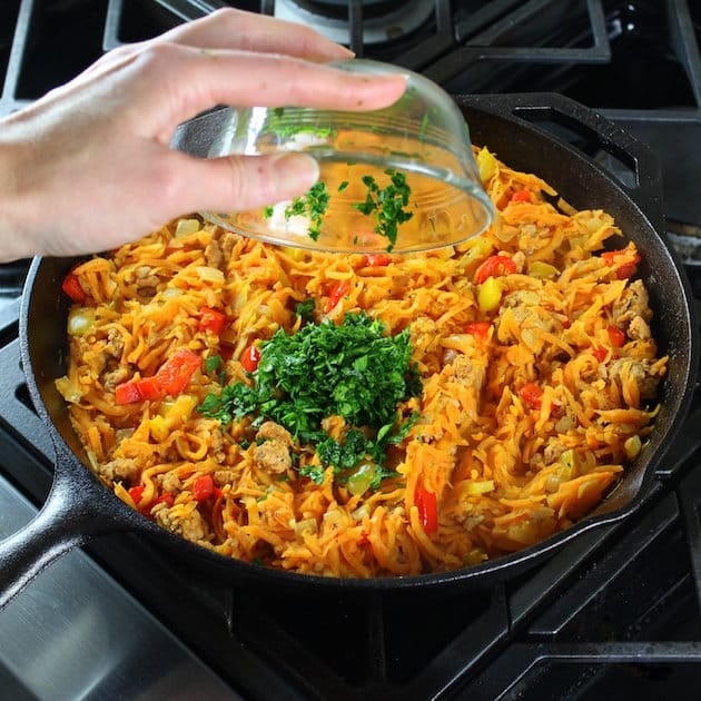 Adding chopped parsley to breakfast skillet