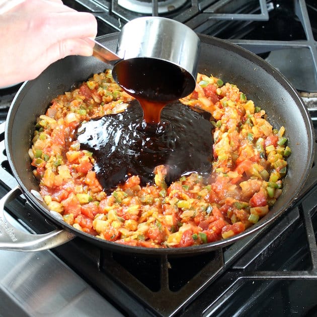 Adding hoisin sauce to asian ingredients on stovetop
