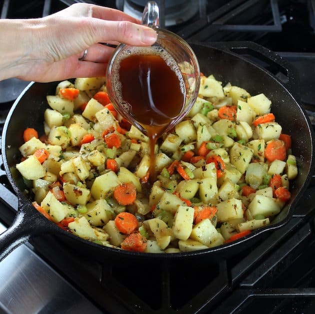 A pan filled with meat and vegetables cooking on a stove