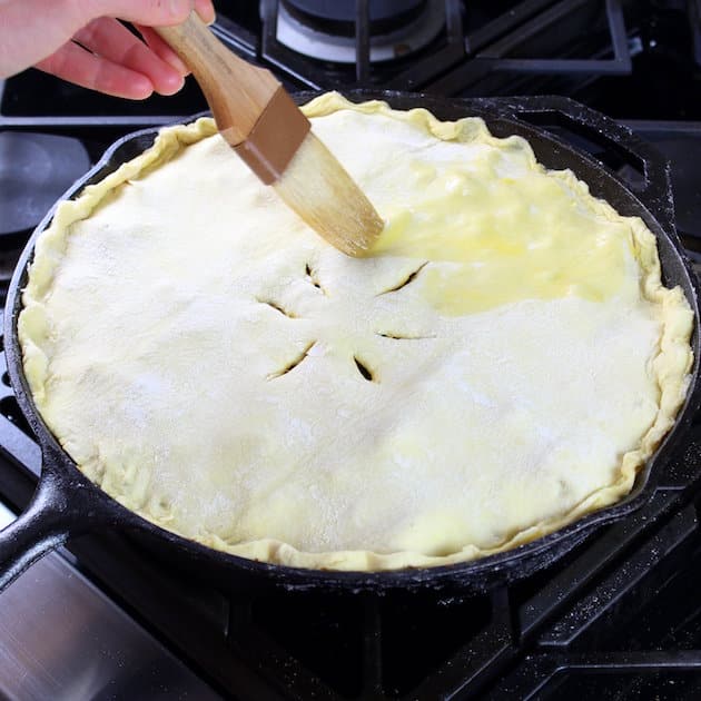 Brushing egg wash on top of pie before baking