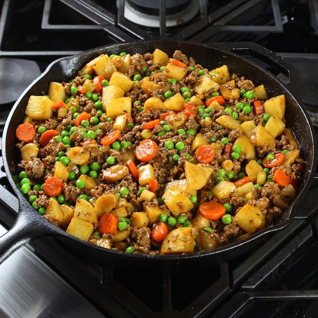 A pan filled with meat and vegetables cooking on a stove