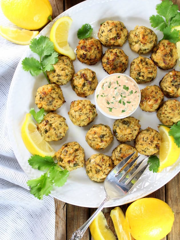 Tuna cakes and sauce on platter with lemon garnishes