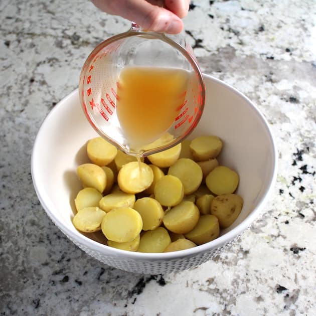Adding liquids to a bowl of baby potatoes