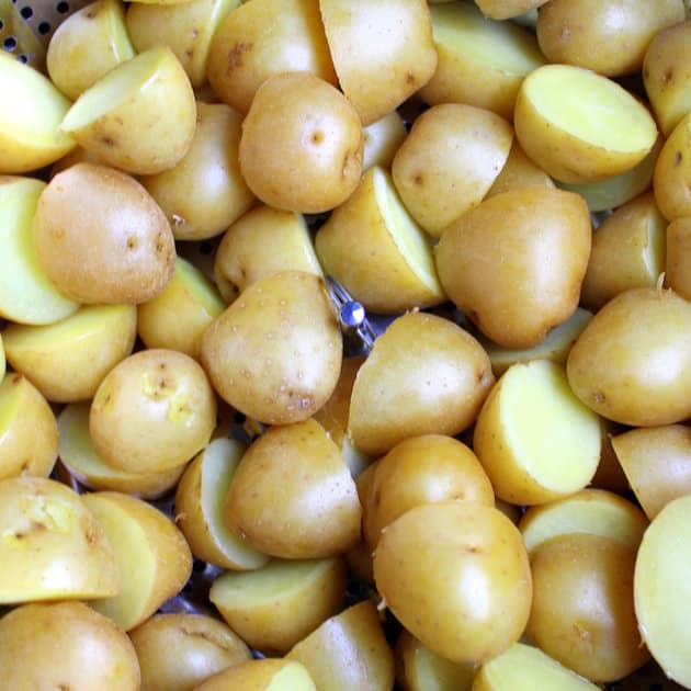 rinsed baby dutch potatoes cut in half in a steamer basket