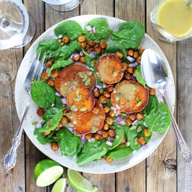 Plate of salad with dressing, fresh limes and water glass on farm table